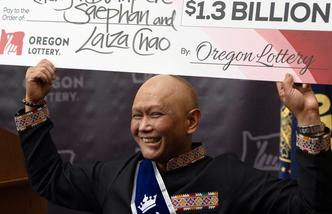 Cheng Saephan hält einen Riesencheck in Höhe von 1,3 Milliarden Dollar in die Höhe.<span class='image-autor'>Foto: Jenny Kane/AP/dpa</span>