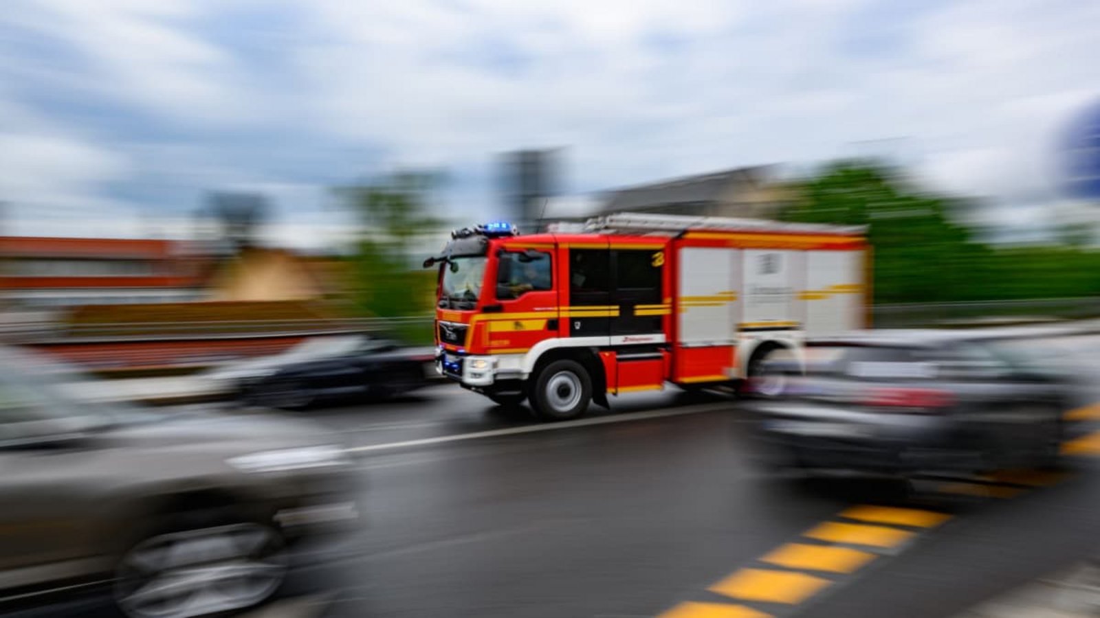Eine Feuerwehrfahrzeug fährt mit Blaulicht zu einem Einsatz.Robert Michael/dpa