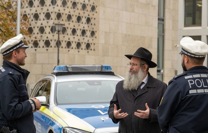Rabbiner Shneur Trebnik und Polizisten unterhalten sich vor der Synagoge in Ulm: Juden werden immer wieder als Hauptverantwortliche für globale Krisen dargestellt.<span class='image-autor'>Foto: dpa/Stefan Puchner</span>