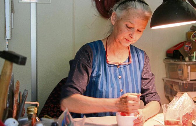 In ihrem kleinen Atelier zerkleinert Annette Wiesner Mohnblüten mit einem Mörser. Aus den roten Blüten wird später eine tiefe, kräftige rote Farbe werden.  Fotos: Thomaser