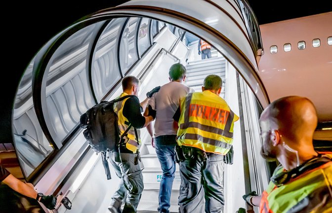 Polizeibeamte begleiten einen Afghanen auf dem Flughafen Leipzig-Halle in ein Charterflugzeug.<span class='image-autor'>Foto: picture alliance/dpa/Michael Kappeler</span>