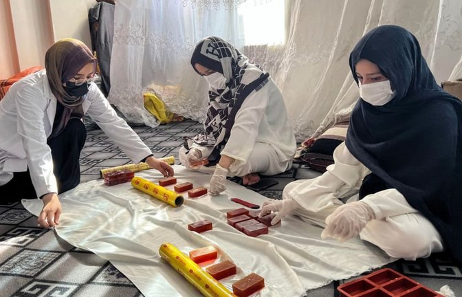 Roqia Rezai (l.) verpackt Seife mit ihren Schwestern in ihrer Seifenfabrik in Herat. Die afghanische Industrie- und Handelskammer erlaubt Frauen teilweise zu arbeiten – wenn sie das von zu Hause aus können.<span class='image-autor'>Fardina Akbari/dpa</span>