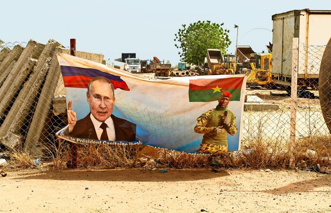 Burkina Faso: An einem Straßenrand hängt ein Plakat  mit dem russischen Präsidenten Wladimir Putin – nicht nur hier sondern auch in anderen  Teilen Afrikas rekrutiert der Kreml Menschen für den Krieg.<span class='image-autor'>Foto: IMAGO/Achille Abboud</span>