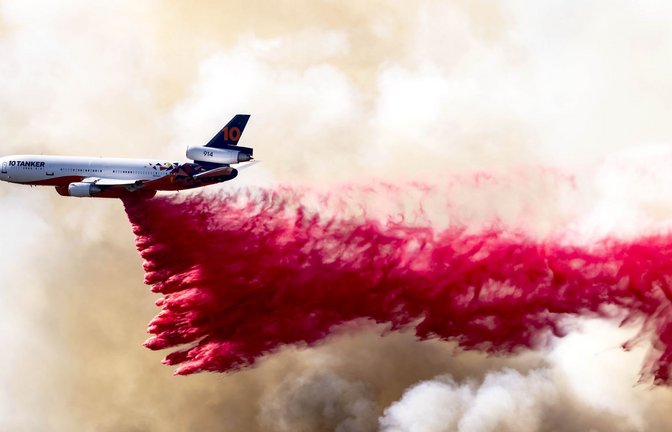 Ein Flugzeug wirft am 11. Januar 2025 eine rote Feuerlöschflüssigkeit aus Phos-Chek-Löschmittel in den Mandeville Canyon bei Los Angeles ab.<span class='image-autor'>Foto: Brian Cahn/Zuma Press Wire/dpa</span>