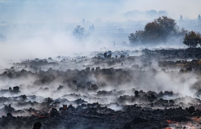 Rauch schwebt über der verbrannten Landschaft im Naturschutzgebiet Hohes Venns. Die Bekämpfung des Waldbrandes ist wegen des torfhaltigen Bodens in dem Naturschutzgebiet besonders schwierig.<span class='image-autor'>Bruno Fahy/Belga/dpa</span>
