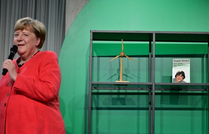 Angela Merkel (CDU), Bundeskanzlerin a.D. und ehemalige Bundesumweltministerin, spricht auf der Bühne beim Festakt "Seit 40 Jahren NaturVerbunden" zum 40. Jubiläum des Bundesumweltministeriums im Café "Moskau", während im Hintergrund ihr Buch mit dem Titel „Der Preis des Überlebens“ zu sehen ist.<span class='image-autor'>Foto: Sebastian Christoph Gollnow/dpa</span>