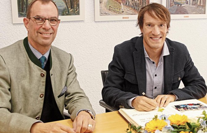 Sebastian Kienle (rechts) trägt sich nach seinem dritten Platz bei der Triathlon-WM auf Hawaii im Beisein von OB Frank Schneider zum wiederholten Mal ins Goldene Buch der Stadt Mühlacker ein. Foto: Kollros