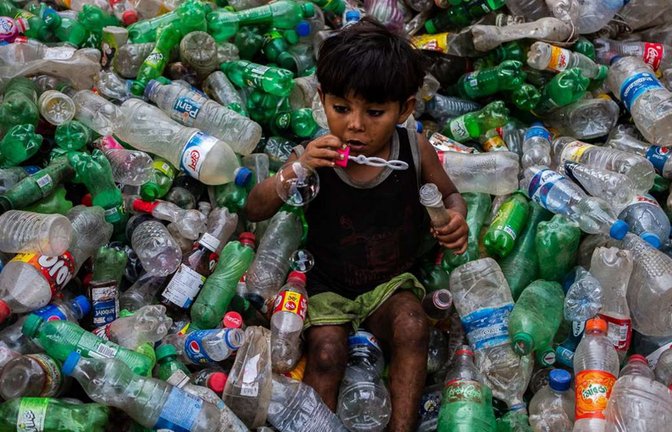 Ein Junge pustet Seifenblasen auf einem Stapel von Plastikflaschen in einer Recycling-Anlage in Dhaka (Bangladesch).<span class='image-autor'>Foto: Nayem Shaan/ZUMA Wire/dpa</span>