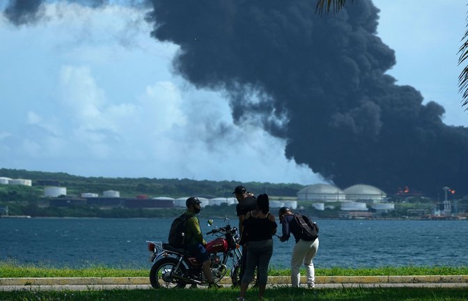 Menschen beobachten eine riesige aufsteigende Rauchwolke aus der Matanzas Supertanker-Basis.<span class='image-autor'>Foto: Ramon Espinosa/AP/dpa</span>