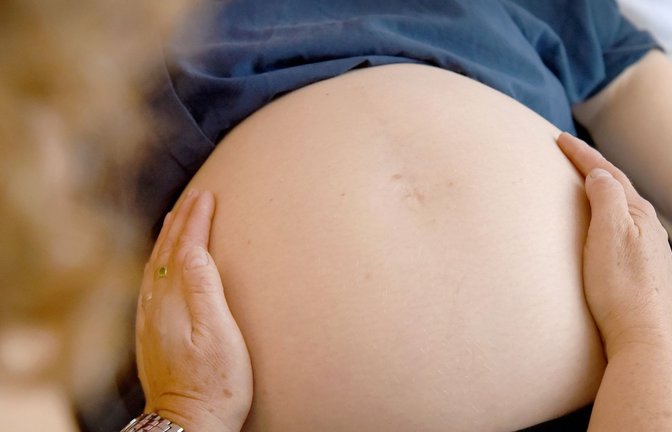 Eine Hebamme tastet den Bauch einer Frau ab, die im neunten Monat schwanger ist.<span class='image-autor'>Foto: Caroline Seidel/dpa</span>