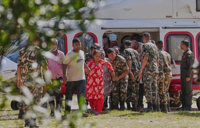 Soldaten der Armee helfen einer Familie beim Aussteigen aus einem Hubschrauber, nachdem sie aus einem von Sturzfluten betroffenen Gebiet im nepalesischen Distrikt Nuwakot gerettet wurden.<span class='image-autor'>Rajesh Kumar Singh/AP/dpa</span>