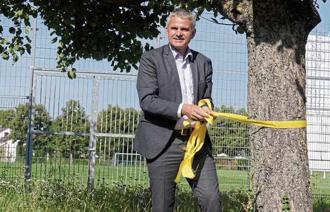 Bürgermeister Holger Albrich bringt ein gelbes Band an. Foto: p