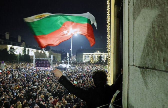 Ein Student schwenkt eine bulgarische Flagge, während eine anschwellende Menge von Zehntausenden von Bulgaren den zentralen Platz in Sofia füllt und den Rücktritt der Regierung inmitten wachsender Wut über Korruption und umstrittene Wirtschaftspolitik fordert.<span class='image-autor'>Foto: dpa/Valentina Petrova</span>