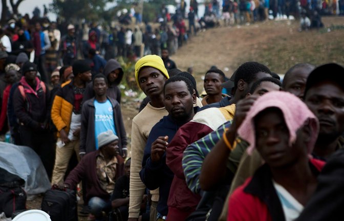 Vertriebene Migranten stehen in Durban in Südafrika vor einer Abschiebeeinrichtung Schlange.<span class='image-autor'>Foto: Uncredited/AP/dpa</span>