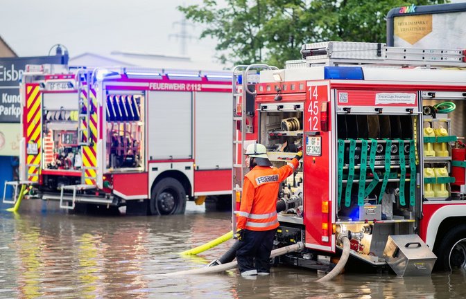 Zwei Einsatzfahrzeuge der niedersächsischen Feuerwehr stehen im Juni 2020 auf dem überschwemmten Parkplatz eines Supermarktes, der wegen Starkregen abgepumpt werden muss.<span class='image-autor'>Foto: Hauke-Christian Dittrich/dpa</span>