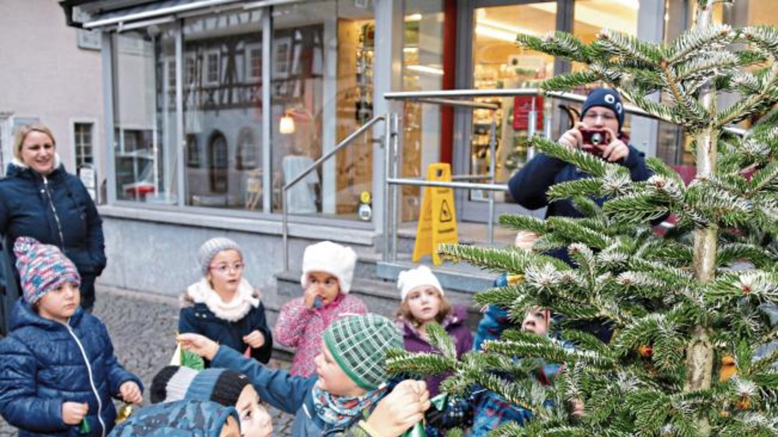 Vor dem Dorfladen in Enzweihingen wurde gestern Morgen der Weihnachtsbaum vom katholischen Kindergarten geschmückt. Der Dorfladen beteiligt sich an der Aktion der Werbegemeinschaft Vaihingen, einen Weihnachtsbaum vor dem Geschäft aufzustellen und ihn von Kindern dekorieren zu lassen. Foto: Bögel Vor dem Dorfladen in Enzweihingen wurde gestern Morgen der Weihnachtsbaum vom katholischen Kindergarten geschmückt. Der Dorfladen beteiligt sich an der Aktion der Werbegemeinschaft Vaihingen, einen Weihnachtsbaum vor dem Geschäft aufzustellen und ihn von Kindern dekorieren zu lassen. Foto: Bögel