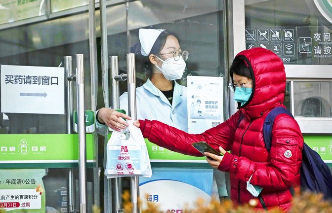 Eine Frau holt in einer Apotheke in Peking Covid-19-Antigen-Kits ab.<span class='image-autor'>Foto: dpa/Andy Wong</span>