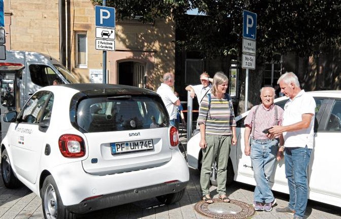 Am Standplatz vor dem Bahnhof in Mühlacker erläutert Thomas Knapp (rechts) die Vorgehensweise, wie man per App zu einem elektrobetriebenen Unomondo-Leihfahrzeug kommt. Foto: Kollros