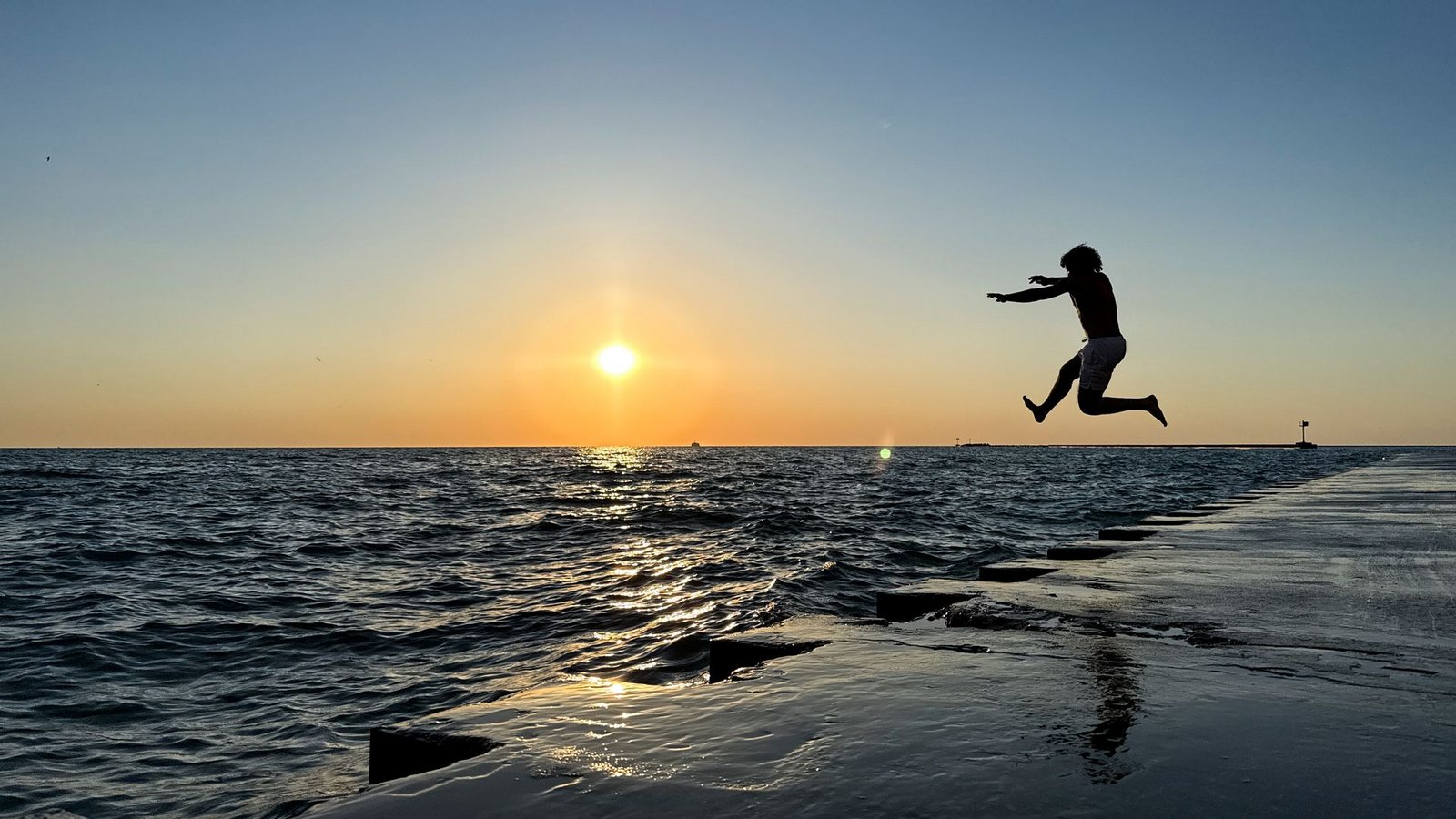 Ein junger Mann springt am frühen Morgen in Chicago von der Promenade am „Oak Street Beach“ in den Lake Michigan.Foto: Christian Charisius/dpa Ein junger Mann springt am frühen Morgen in Chicago von der Promenade am „Oak Street Beach“ in den Lake Michigan.Foto: Christian Charisius/dpa