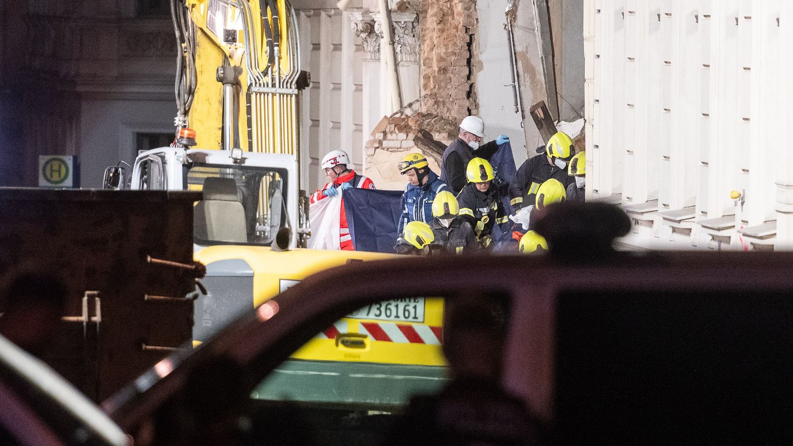 Einsatzkräfte der Feuerwehr tragen hinter Sichtschutz eine Leiche aus dem Trümmerfeld eines eingestürzten Hauses in Görlitz.Foto: Paul Glaser/dpa
