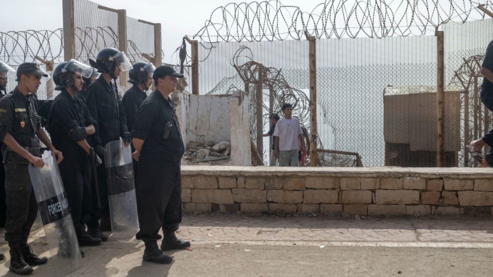 Marokkanische Sicherheitskräfte stehen neben einem durchbrochenen Stacheldrahtzaun Wache, während Menschen, die versucht hatten, nach Ceuta, Spanien, zu gelangen, in die nordmarokkanische Stadt Fnideq zurückkehren (Archivfoto).STR/AP/dpa Marokkanische Sicherheitskräfte stehen neben einem durchbrochenen Stacheldrahtzaun Wache, während Menschen, die versucht hatten, nach Ceuta, Spanien, zu gelangen, in die nordmarokkanische Stadt Fnideq zurückkehren (Archivfoto).STR/AP/dpa