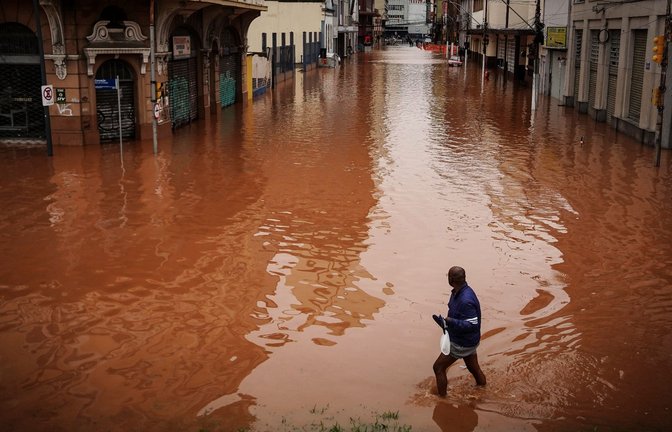 Ein Mann watet in Porto Alegre im brasilianischen Bundesstaat Rio Grande do Sul durch ein von schweren Regenfällen überschwemmtes Gebiet.<span class='image-autor'>Foto: Carlos Macedo/AP/dpa</span>