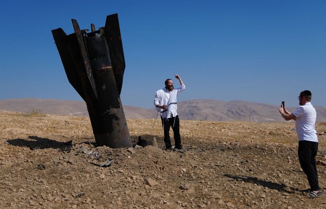 Menschen neben dem Wrack einer iranischen Rakete, die im Westjordanland eingeschlagen ist.<span class='image-autor'>Foto: Mahmoud Illean/AP/dpa</span>