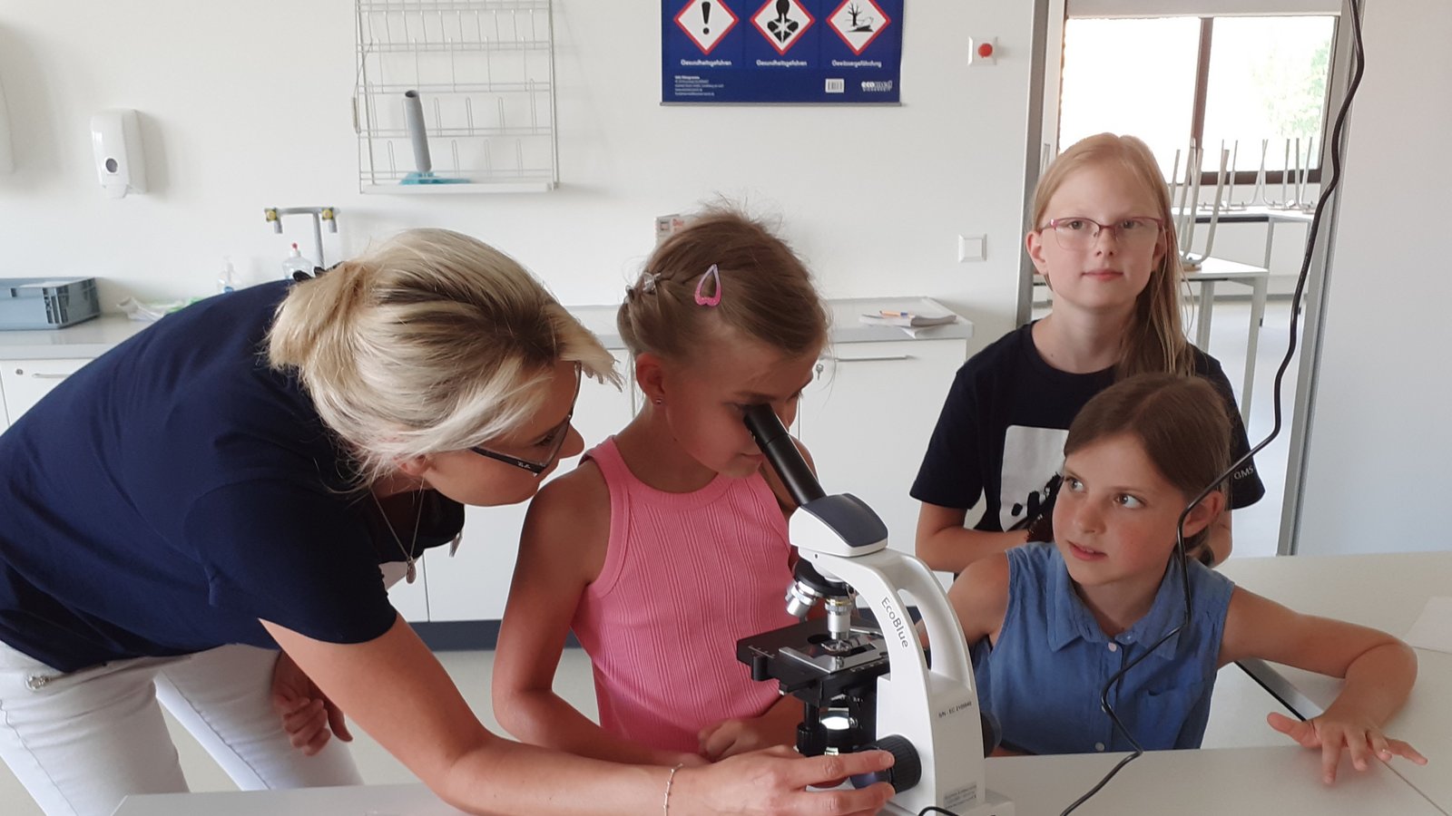 Lehrerin Jasmin Klein zeigt im Naturwissenschaftsraum den kleinen Besuchern des Schulfests der Gemeinschaftsschule Sachsenheim, wie ein Mikroskop richtig bedient wird.  Foto: Glemser