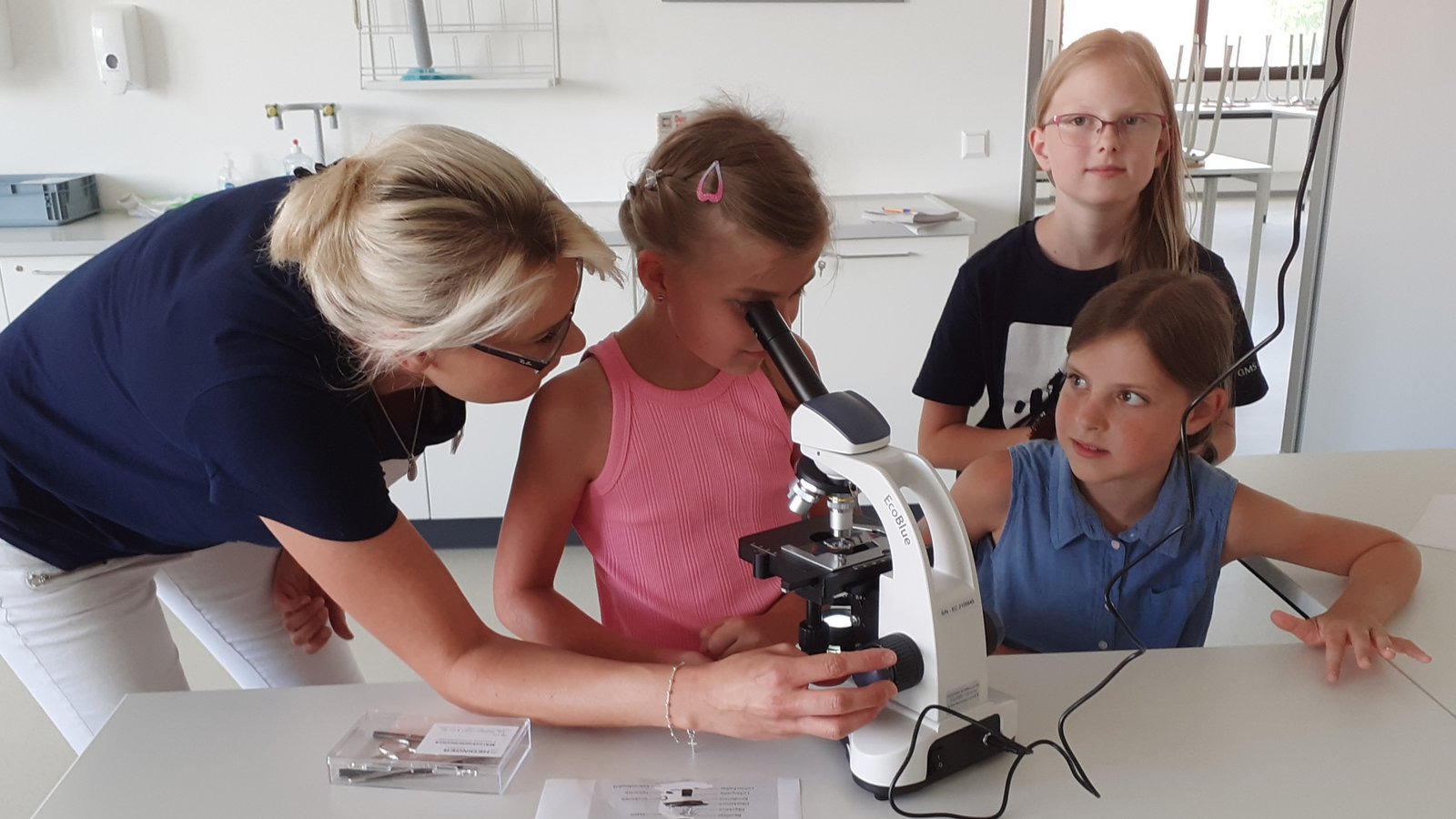 Lehrerin Jasmin Klein zeigt im Naturwissenschaftsraum den kleinen Besuchern des Schulfests der Gemeinschaftsschule Sachsenheim, wie ein Mikroskop richtig bedient wird.  Foto: Glemser