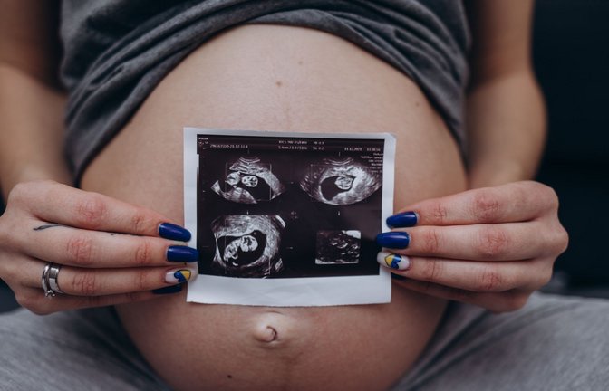 Eine werdende Mutter zeigt Ultraschallaufnahmen des heranwachsenden Babys in ihrem Mutterleib. (Symbolbild)<span class='image-autor'>Foto: IMAGO/Pond5 Images/IMAGO/xfentonromax</span>
