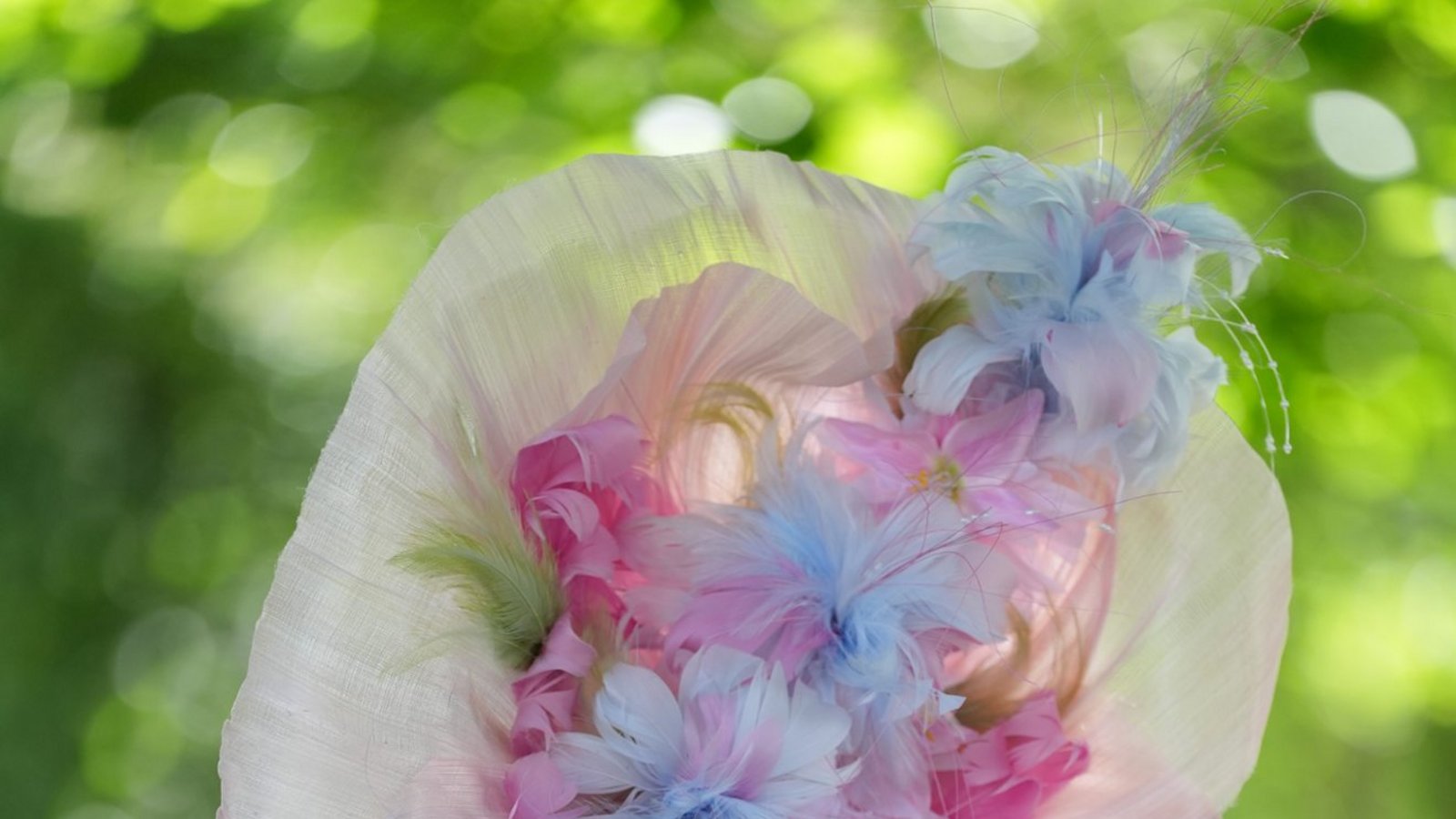 Eine Besucherin von Royal Ascot trägt einen pastellfarbenen Blütenhut in Rosa, Hellblau und Creme, der das Gesicht fast vollständig verdeckt. Das florale Motiv setzt sich im zarten Kleid mit Tüllträgern und Stickereien fort.Foto: picture alliance/dpa/PA Wire | Jonathan Brady