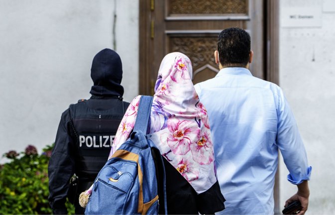 Ein Polizist begleitet zwei Personen   während einer Razzia auf das Gelände vom Islamischen Zentrum Hamburg (IZH).<span class='image-autor'>Foto: dpa/Andreas Arnold</span>
