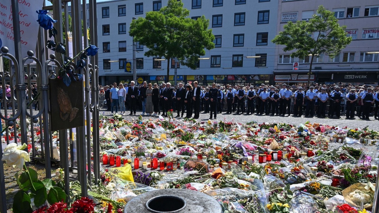 Gedenkfeier für Rouven Laur auf dem Mannheimer Marktplatz. Von den beiden Bäumen, unter denen die Polizisten stehen, lief am Tattag Youssuf Hanash los, um sich dem Attentäter entgegenzustellen und zu helfen.Foto: dpa/Bernd Weißbrod Gedenkfeier für Rouven Laur auf dem Mannheimer Marktplatz. Von den beiden Bäumen, unter denen die Polizisten stehen, lief am Tattag Youssuf Hanash los, um sich dem Attentäter entgegenzustellen und zu helfen.Foto: dpa/Bernd Weißbrod