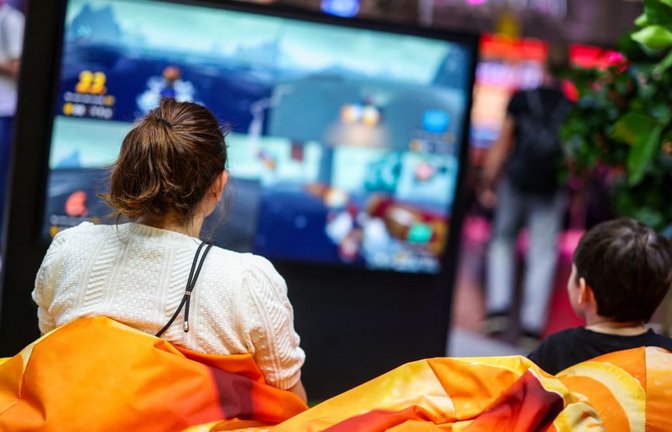Zwei Besucher der Messe Gamescom sitzen auf Sitzsäcken vor einem Bildschirm und spielen ein Videospiel. Künstliche Intelligenz verändert das Spielen.<span class='image-autor'>Christoph Reichwein/dpa</span>