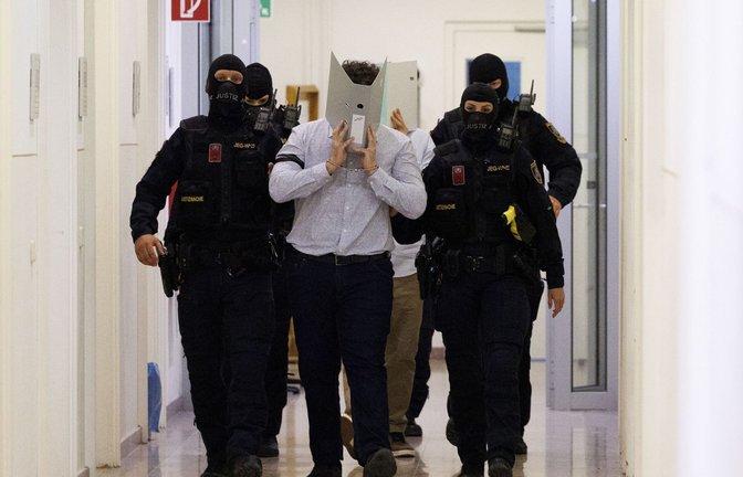 Der Angeklagte im Prozess um mutmaßliche Anschlagspläne auf das Wiener Taylor-Swift-Konzert wird von Polizei im Gericht begleitet.<span class='image-autor'>Foto: Tobias Steinmaurer/APA/dpa/Tobias Steinmaurer</span>
