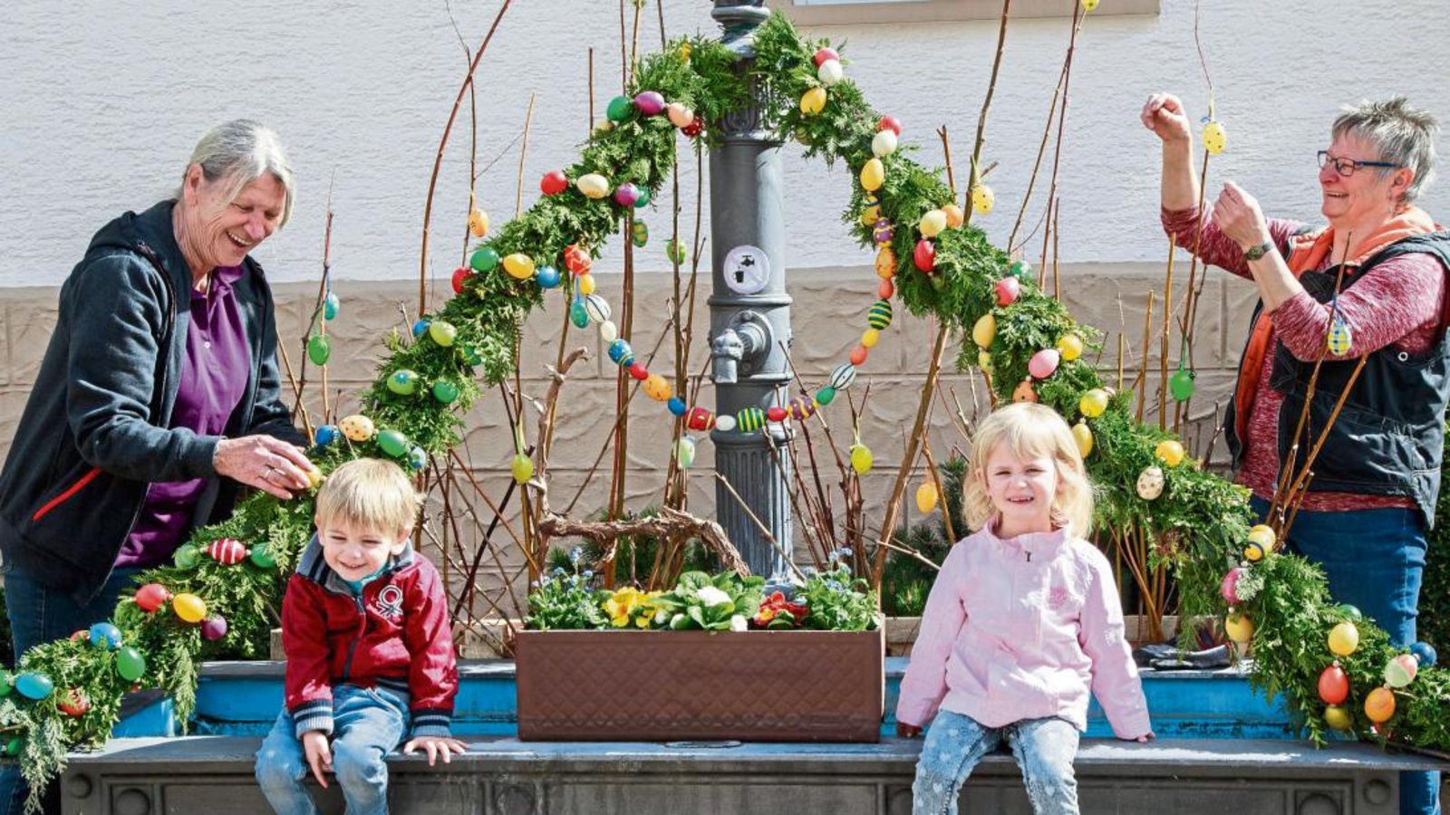 Suse Herrmann (links) mit Enkeln und Petra Pfeiffer behängten den Hohenhaslacher Brunnen mit Eiern. Foto: Pangerl Suse Herrmann (links) mit Enkeln und Petra Pfeiffer behängten den Hohenhaslacher Brunnen mit Eiern. Foto: Pangerl