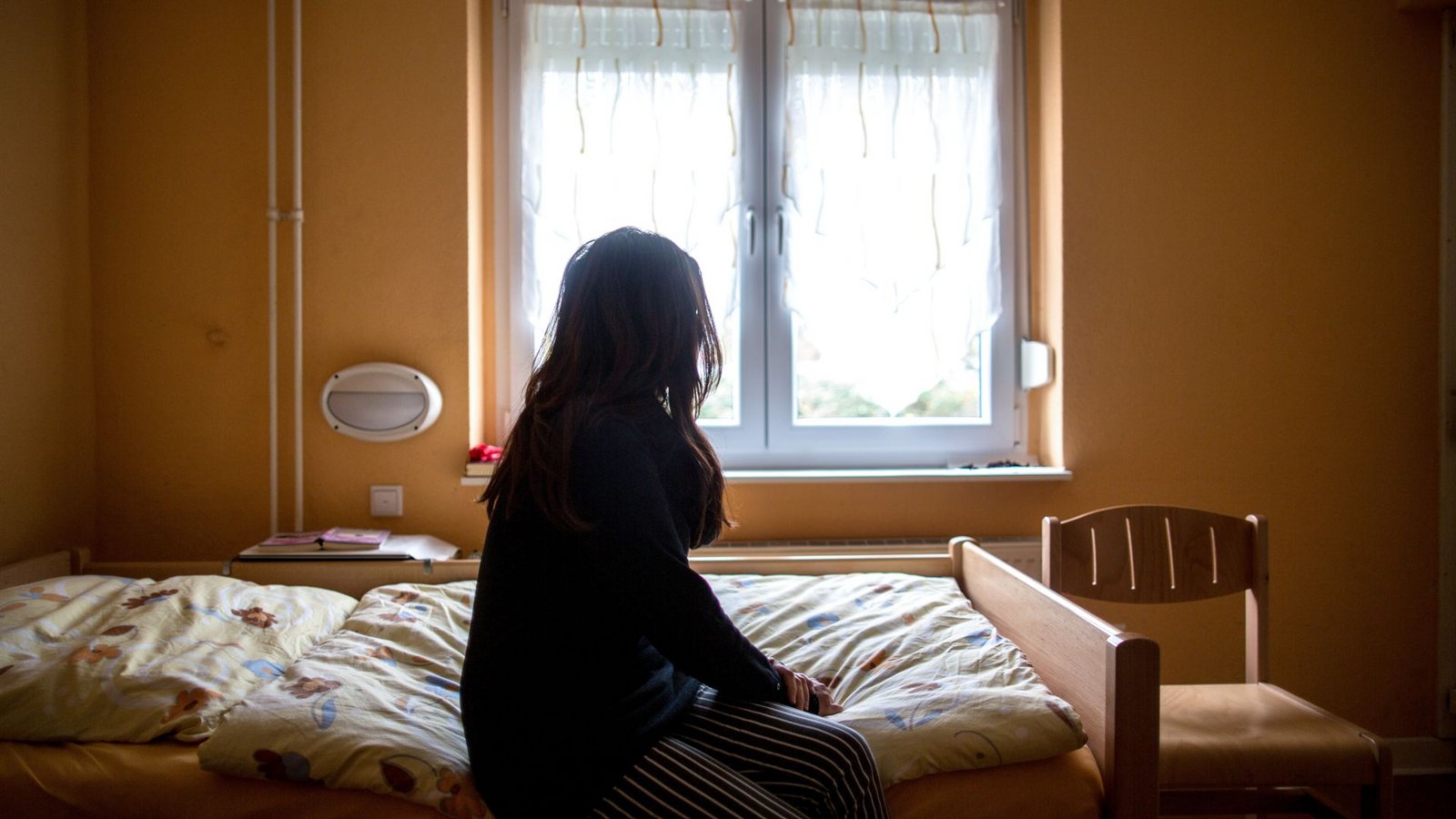 Eine Frau sitzt in einem Frauenhaus auf einem Bett. In Deutschland fehlen über 13.000 Frauenhausplätze (Symbolfoto).Foto: picture alliance/dpa/Maja Hitij