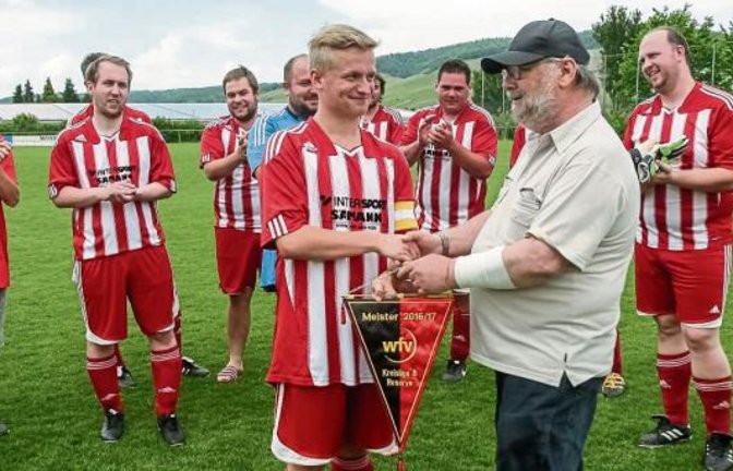 Staffelleiter Bernd Stäcker (vorne rechts) übergibt den Meisterwimpel an Florian Schulz, den Spielführer des TSV Großglattbach II. Foto: Simecek
