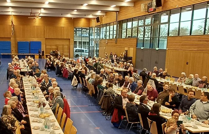 Viele Gäste an den schön gedeckten Tafeln in der Sport- und Kulturhalle in Sersheim beim Herbstfest – von den Zuschauerrängen schauen Eltern und Geschwister den Kita-Kindern zu.