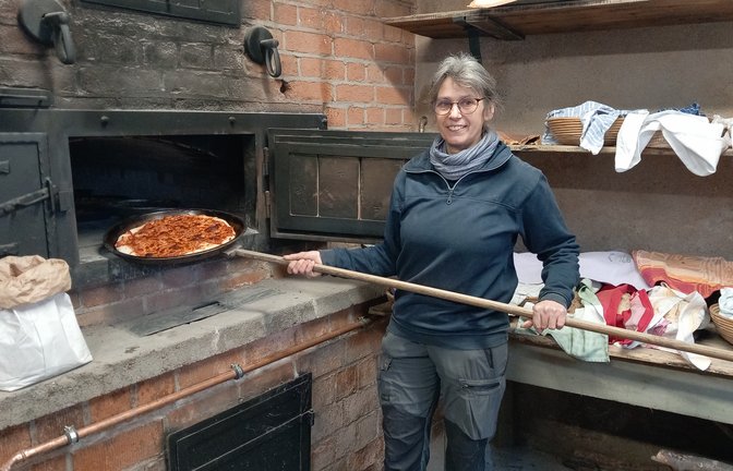 Annette Gummer-Rimmele aus Ochsenbach zieht die erste Pizza aus dem Ofen des Backhauses.  <span class='image-autor'>Foto: Glemser</span>