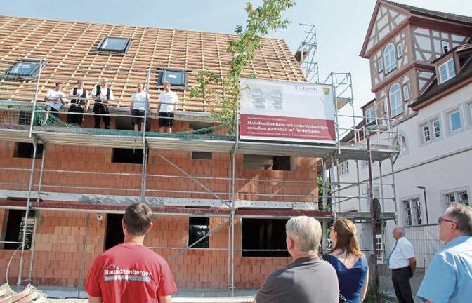 Zimmermeister Stefan Leibfried (auf dem Gerüst in der Mitte) hielt den Richtspruch für den Neubau in unmittelbarer Nähe zum Rathaus, das rechts zu sehen ist.  Foto: Banholzer