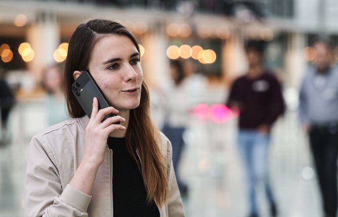 Die für KI zuständige Telekom-Mitarbeiterin Lena Drubel führt bei einer Testvorführung des KI-Assistenten ein Handytelefonat.<span class='image-autor'>Foto: Oliver Berg/dpa</span>