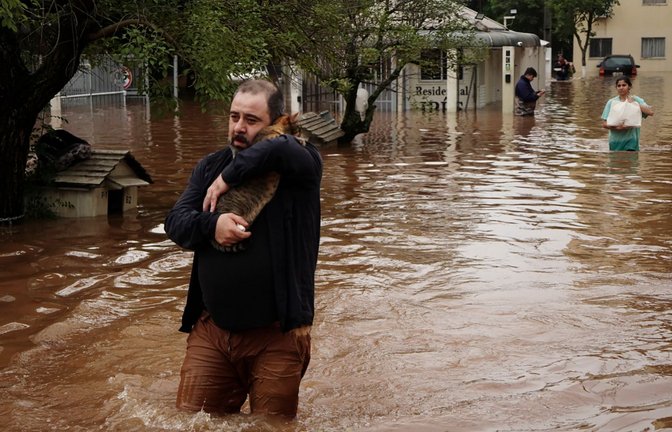 Ein Mann watet durch eine überschwemmte Straße in Brasilien.<span class='image-autor'>Foto: Carlos Macedo/AP</span>