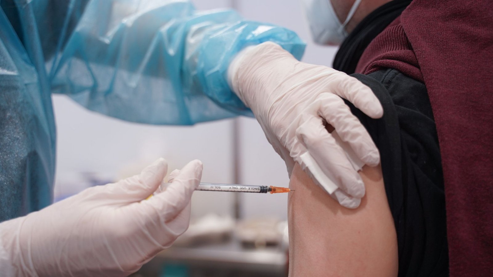 Ein junger Mann wird mit einer Booster-Dosis eines Corona-Impfstoffs in einem Impfzentrum in Potsdam gegen das Coronavirus geimpft.Foto: dpa/Jörg Carstensen