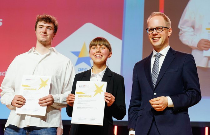 Maja Leber und Julius Gutjahr, Sieger beim Preis des Bundeskanzler, stehen bei der Siegerehrung zum 59. „Jugend forscht“-Bundesfinale mit Laudator Jens Brandenburg, Staatssekretär beim Bundesbildungsministerium, auf der Bühne.<span class='image-autor'>Foto: Uwe Anspach/dpa/Uwe Anspach</span>