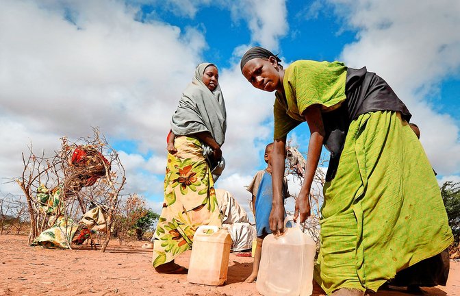Somalische Frauen tragen  ihre tägliche Ration an Trinkwasser zu ihren Zelten im Flüchtlingslager in Dadaab (Kenia).<span class='image-autor'>Foto: dpa/Boris Roessler</span>