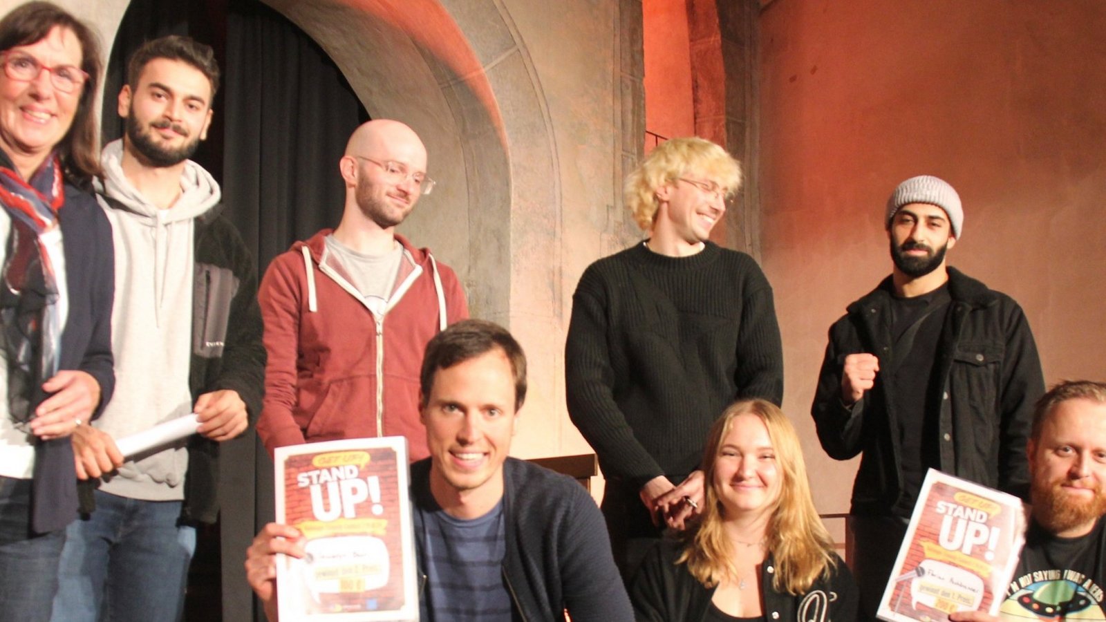 Ulrike Conle (links) vom Verein Drehscheibe, Jugend und Kultur verkündet die Gewinner des zweiten Vaihinger Comedy Contests. Florian Pechbrenner (untere Reihe rechts) landet auf dem ersten Platz. Seweryn Baur (links unten) wird Zweiter und Stephanie Zöllner Dritte. Joni Zwick (obere Reihe, Zweiter von rechts) war im vergangenen Jahr Dritter geworden und moderiert in diesem Jahr den Contest. Neben ihm stehen die anderen Comedy-Talente: Wisam Mamoka, Manuel Striebel und Daniel Ghassemi (von rechts).  Fotos: Müller