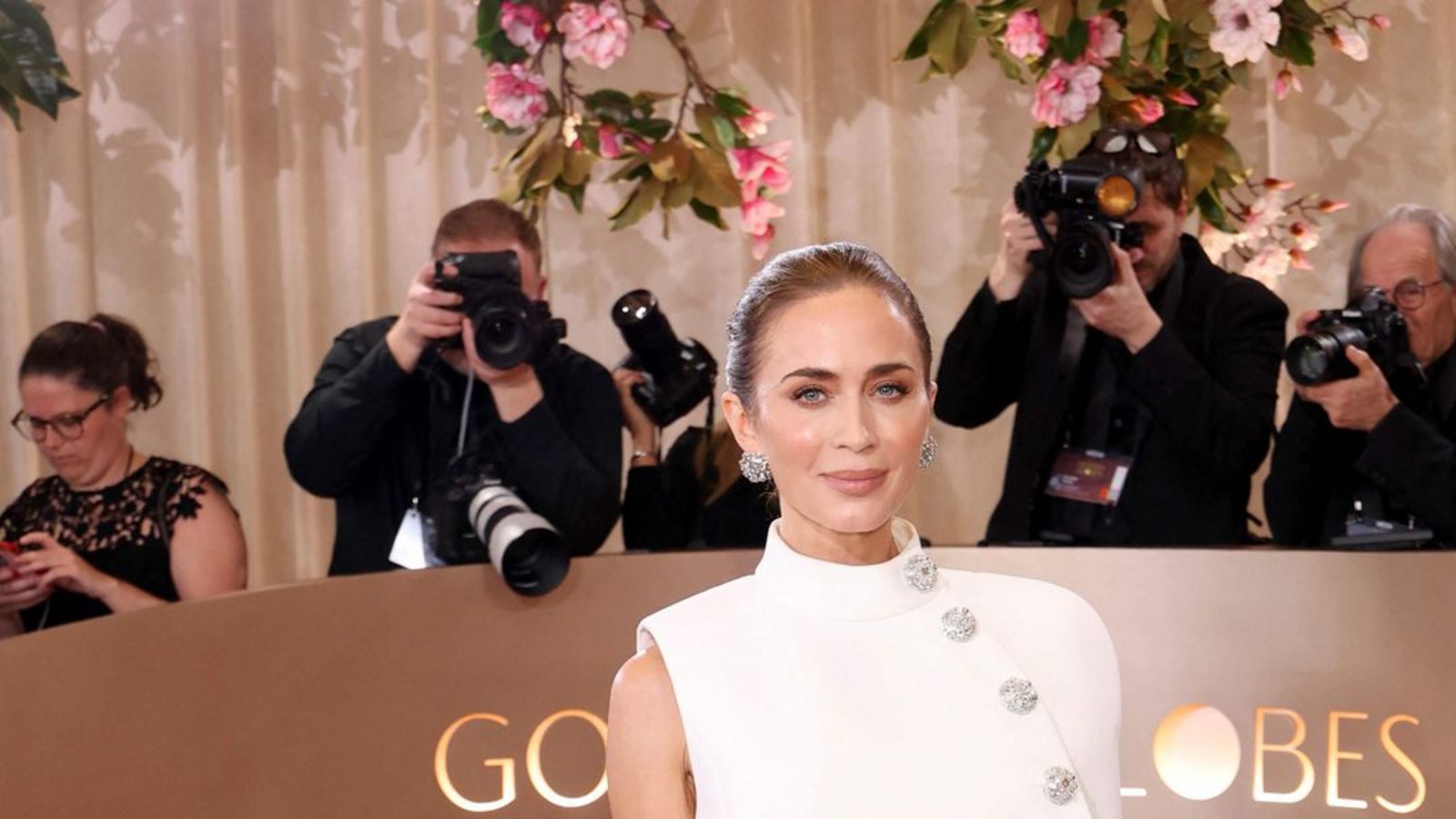 Ein spannendes Ensemble von Louis Vuitton: Emily Blunt trägt über einem extrem schlichten weißen Kleid ein asymmetrisches Cape mit Funkelknöpfen.Foto: Getty Images via AFP