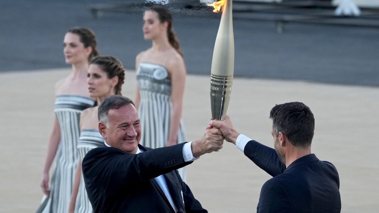 Der Präsident des französischen Organisationskomitees, Tony Estanguet (r), nahm die olympische Flamme in Athen entgegen.Foto: Petros Giannakouris/AP/dpa