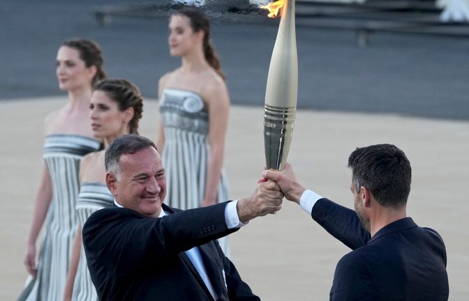 Der Präsident des französischen Organisationskomitees, Tony Estanguet (r), nahm die olympische Flamme in Athen entgegen.<span class='image-autor'>Foto: Petros Giannakouris/AP/dpa</span>